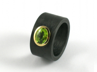 Ring aus Carbon mit einem Peridot gefasst in Gelbgold